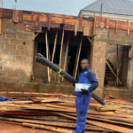 Electrical engineer holding pipes in front of a building site